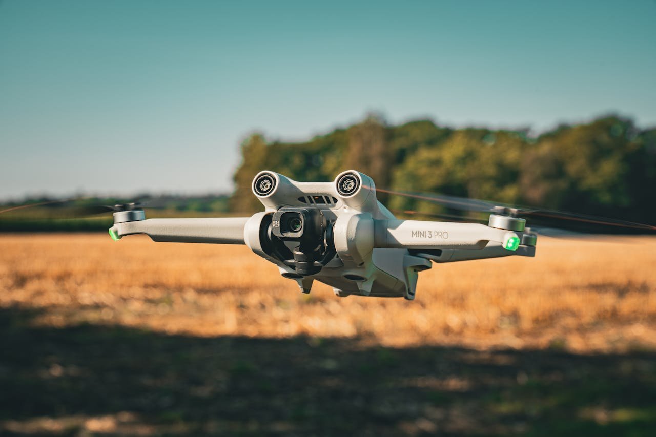 portfolio-img-09 A DJI Mini 3 Pro drone flying over an open field with a clear, blue sky backdrop.
