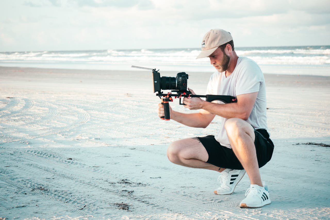 portfolio-img-05 Young filmmaker capturing video on a sandy beach using handheld gear, enjoying the summer outdoors.