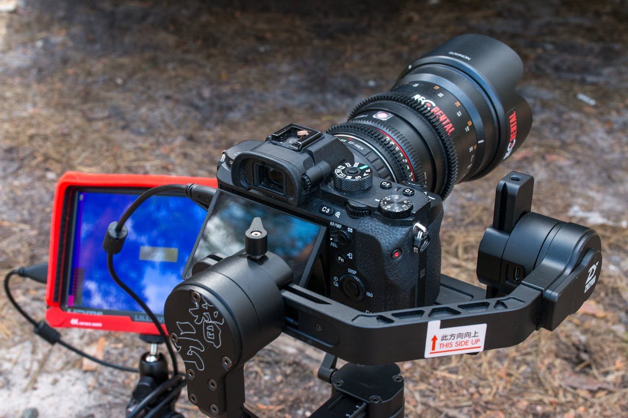 our-services-05 Detailed view of a professional camera with lens and monitor setup, outdoors.